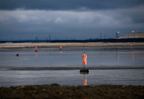 Syncrude tailings pond, dotted with 'Bituman' scarecrows designed to keep migratory birds from landing in the toxic sludge, north of Fort McMurray, Alberta, 2009