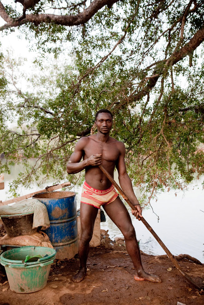 A migrant worker from Guinea with the shovel he uses to excavate sand from the River Gambia in Senegal. The sand will be washed and mixed with mercury to extract gold.