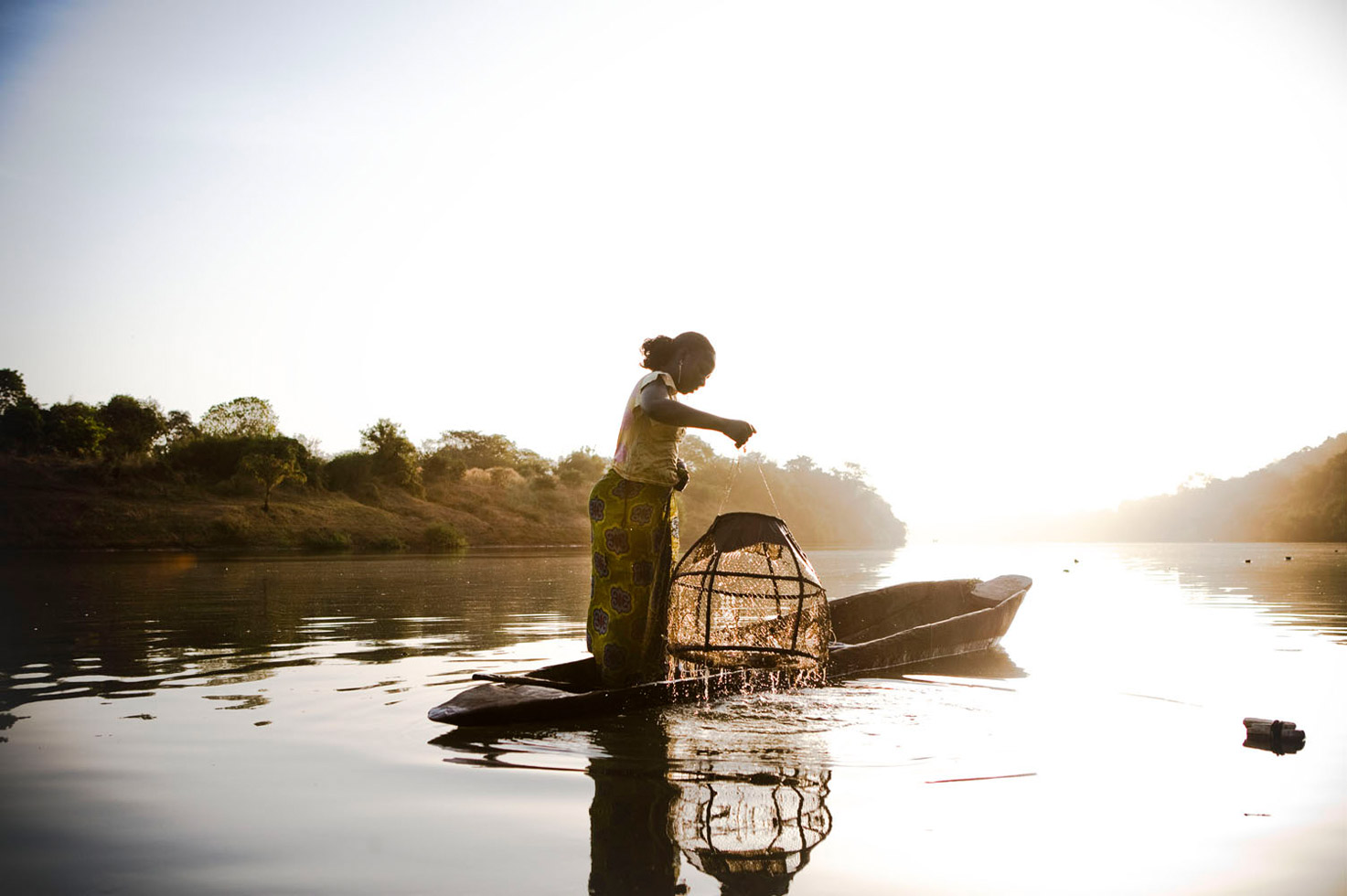 A migrant worker from Mali pulls up the fishing pots from River Gambia, near the Gambian village of Fatoto.