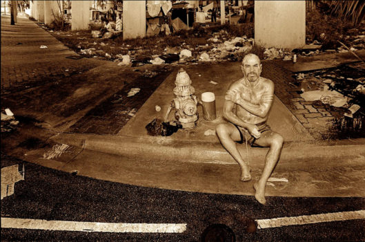 Downtown Miami, Florida, 1993-1994.  
While the city of Miami was being sued in the 1990's for violating the civil rights of homeless people, a judge ordered "safe zones" be established where people could live without fear of arrest. In the photo a man is bathing at a water hydrant in Downtown Miami. This water source also served for drinking water and washing clothes.
