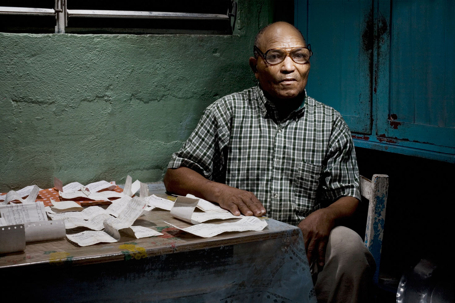 A few years ago, the sugar cane industry offered lifetime pensions to anyone who saved more than 350 pay-stubs during their working lives. Here, Chi Chi proudly shows some of the pay-stubs he saved. He was the only person in the Batey to have saved more than 350, which earned him and his wife, Sonia, a monthly pension of 2,985 pesos.