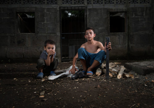 Tipitapa, Nicaragua, 2012
"Bryan is 12 years old and started using a machete at the age of five. He makes 80 cents for half-a-day's work clearing weeds around trees. Here, he poses with his dog, Camilla, and younger brother, Jonathan, as he chops firewood for the family."