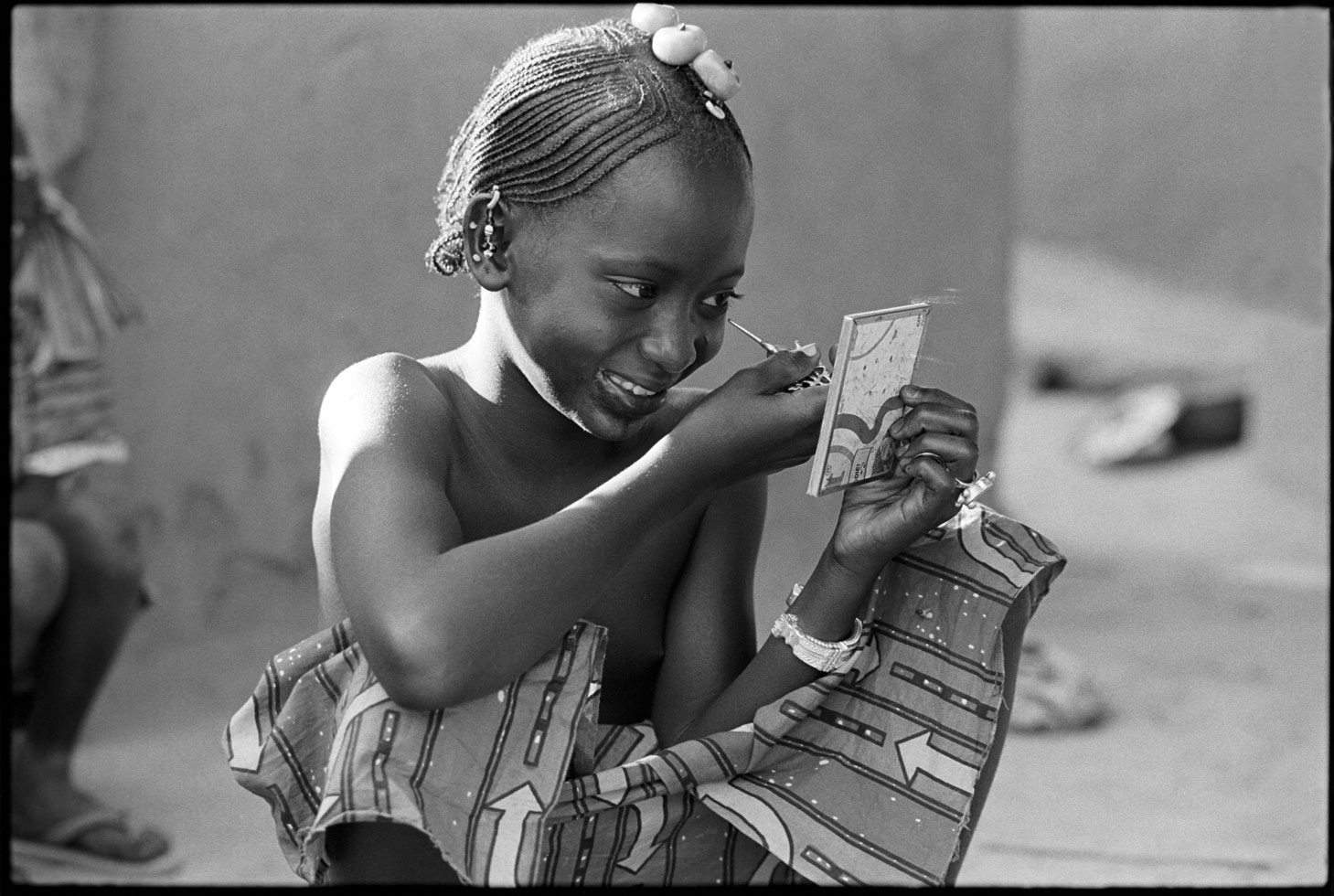 "The world is a mirror; it looks at you the same way you look at it." North African proverb

This young Peul girl prepares for the annual 'Crossing of the Cattle' Festival which takes place along the Niger River. The festival is a celebration of the return of the cattle herders who spent the dry season searching for food for the cattle. The return of the men symbolizes their having attained manhood.

Diafarabé, Mali, 1994