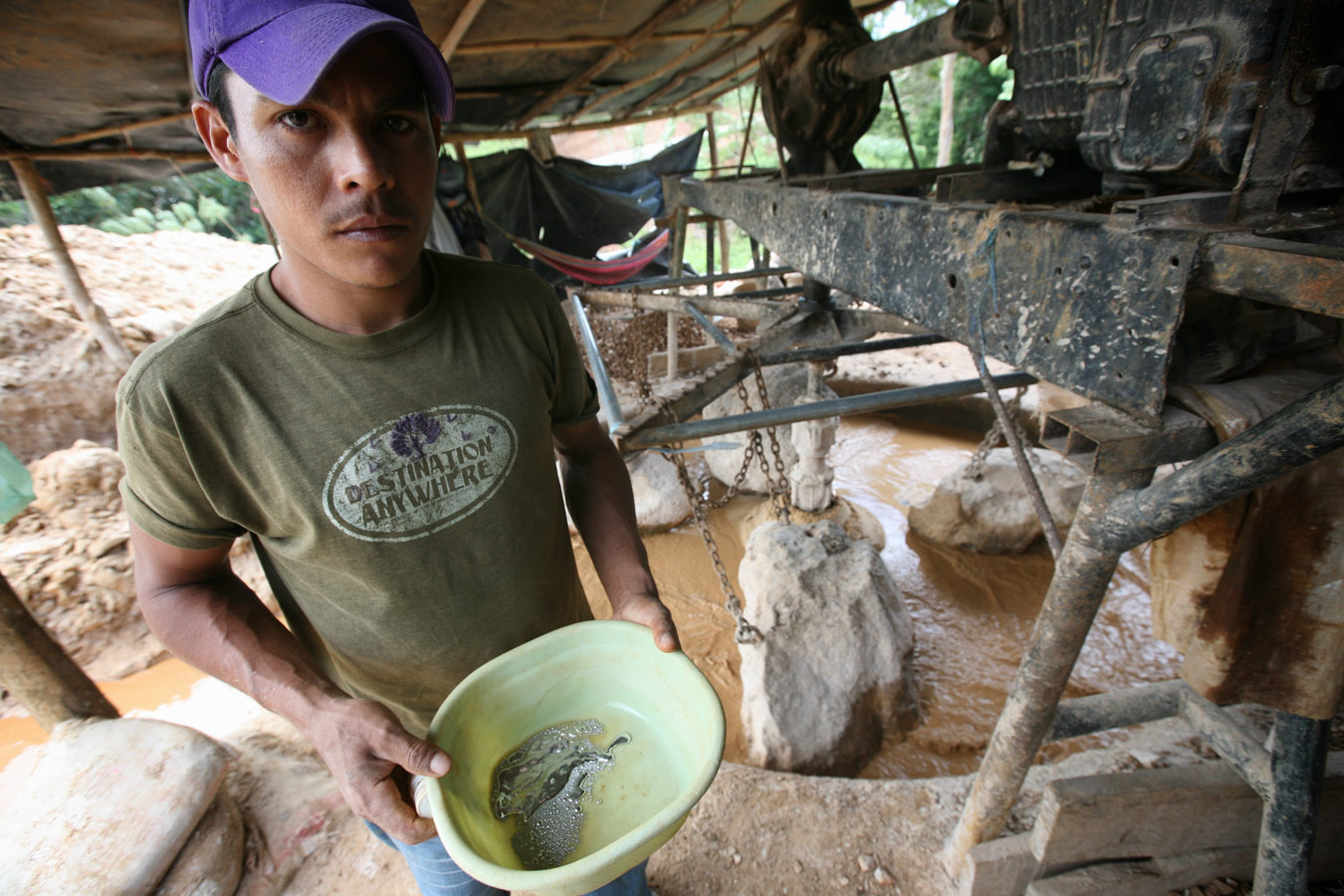 A miner holds a bowl with mercury near an 'arrastra' type gold mill.
