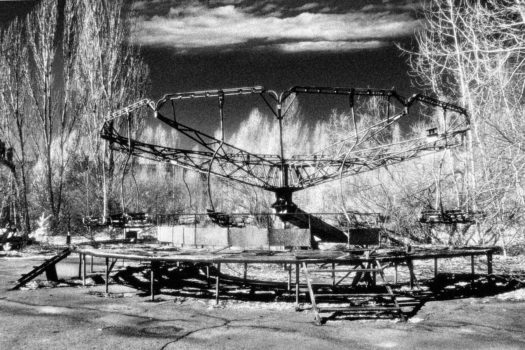 A fairground ride left rusting and rotting, surrounded by concrete and radioactive moss.