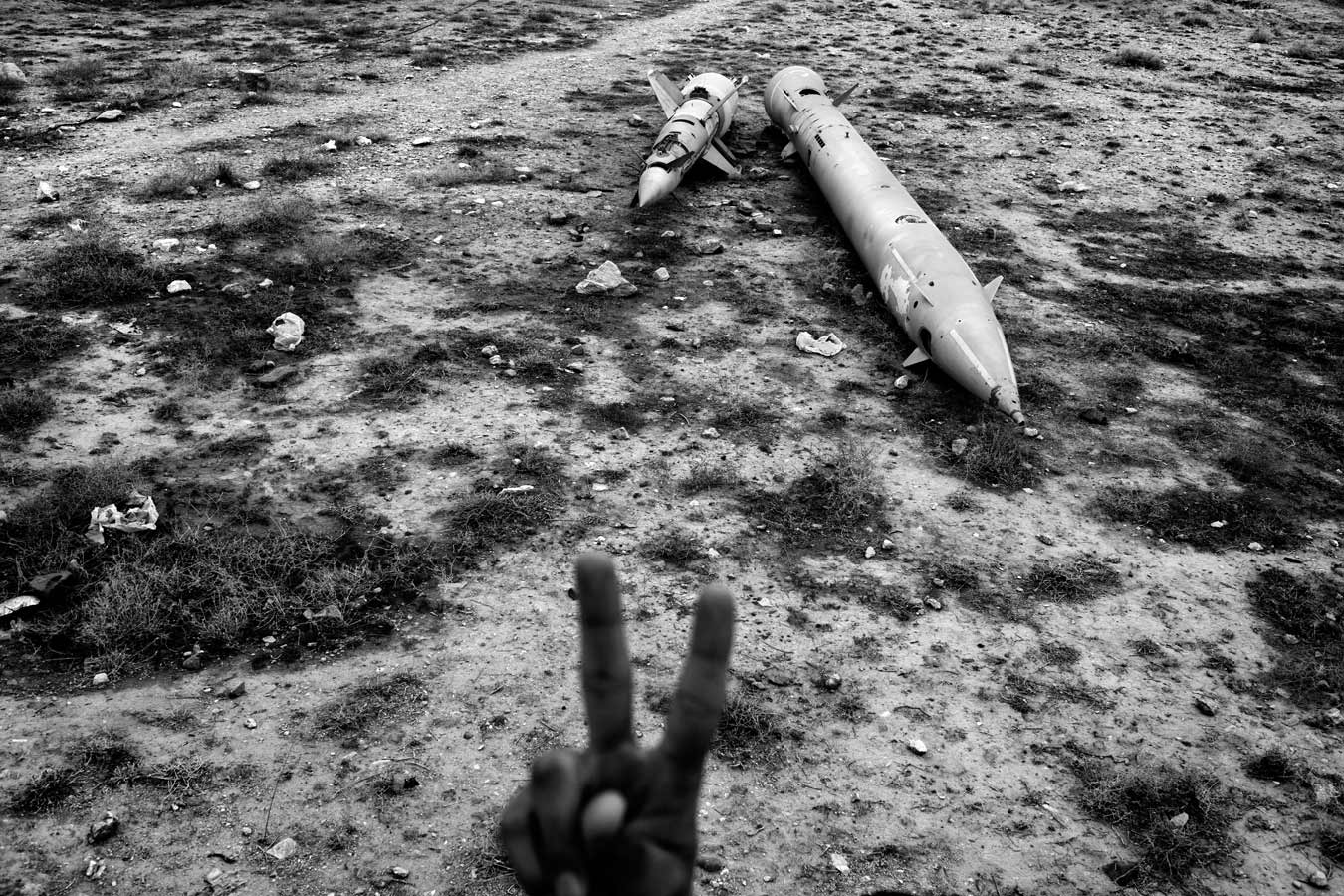 A young Afghan man gestures to the camera as he makes his way past discarded Soviet missiles in Kabul, December 2009. From the series 'Capital'

© Rafal Gersak