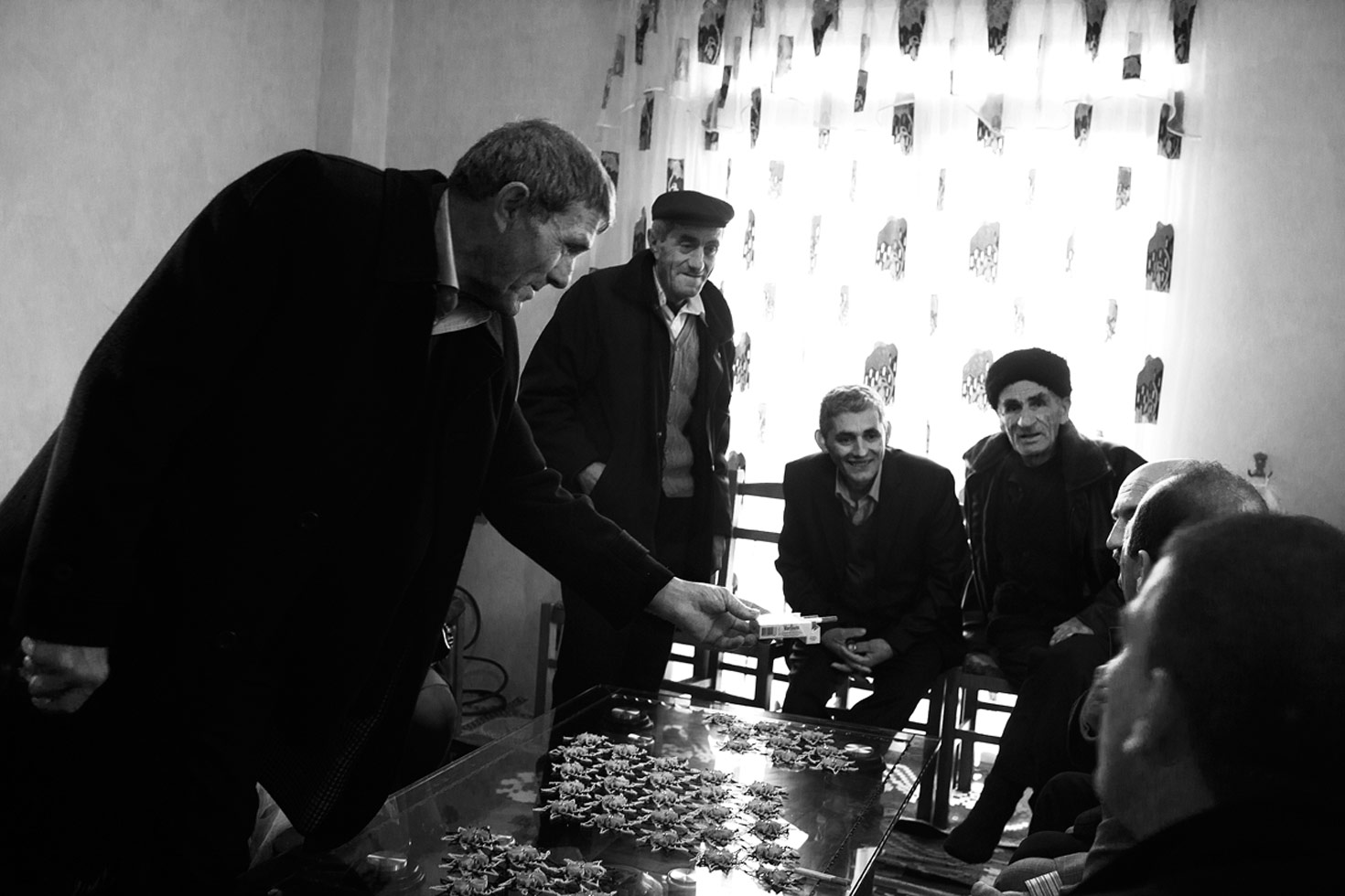 The bride's father offers cigarettes to the groom and his relatives. According to tradition the men have come to take the bride away.

Tirana, Albania, 2012
