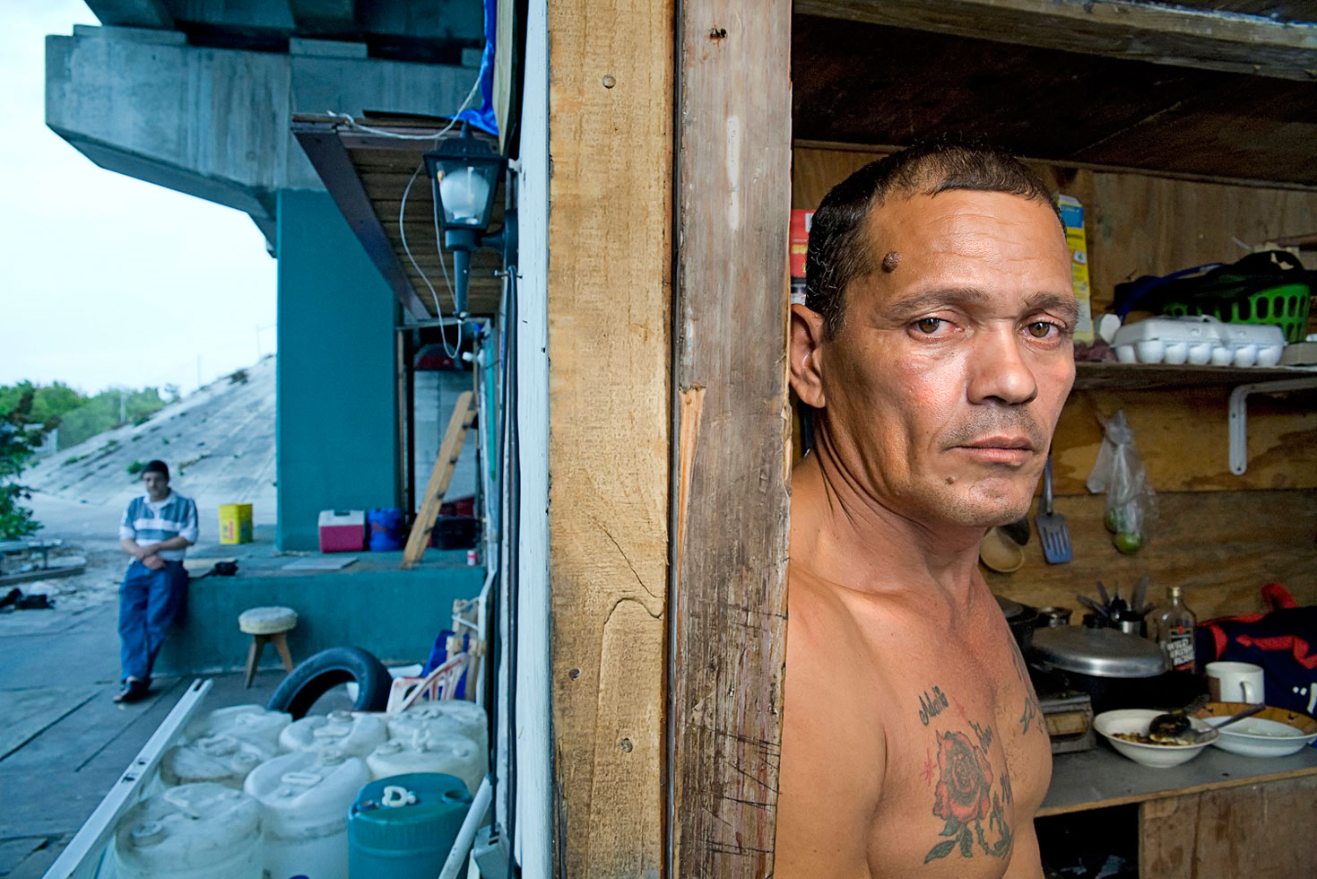 New parolees were released from prison and dropped off at the encampment without so much as a sleeping bag. They are given a little money and they have the clothes they are wearing. Residents would welcome them into the community by offering them an old mattress or blanket. On the left side of the frame is the new arrival.