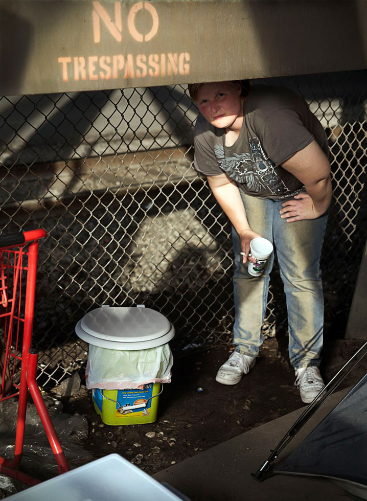 Claiborne Camp, New Orleans, 2014.
Phoenix shows off the ladies' room she created at her encampment. She says the men give her privacy she just has to be sure a train is not coming. Since then they built a little private room with tarp walls. These structures can get swept away by police at any time.