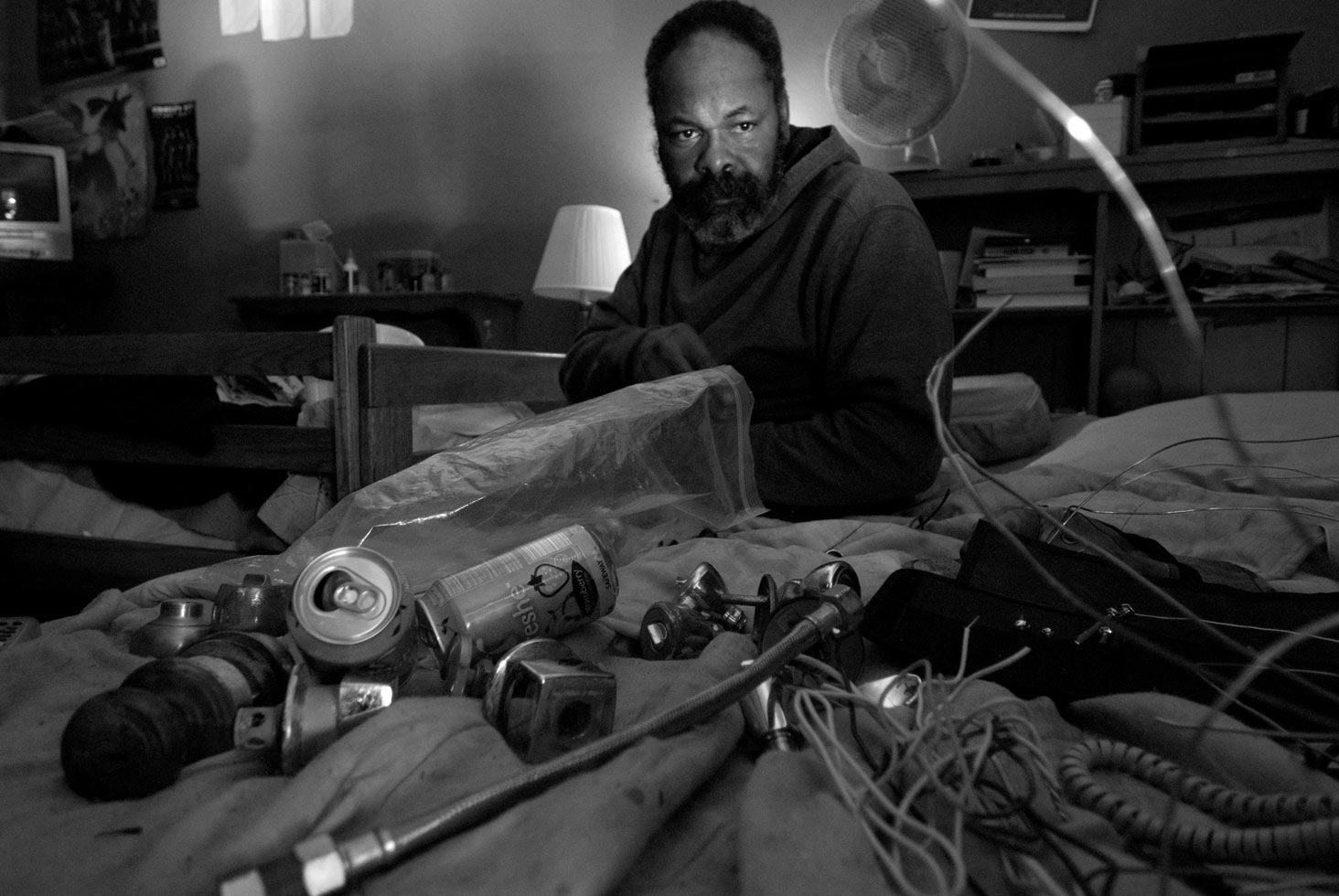 Carlos A. Moreno: Picking Up The Pieces

Mahir takes a moment to reflect as he works on disassembling door knobs for brass and metals. Because they do not have space to work on The Abdullahs frequently place the waste items they find and deconstruct from dumpsters and warehouses on their bed.