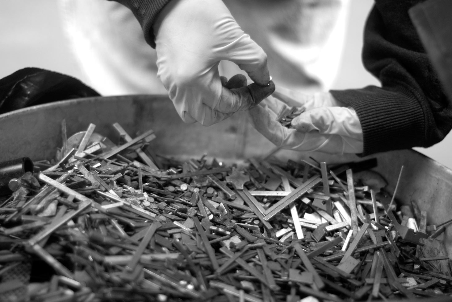 Tasha picking up metals pieces of leftover scrap from a junk yard.