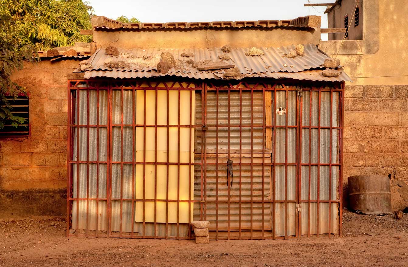 At sunrise and sunset the kiosks become mysterious, glowing rectangles and cubes. I like to walk the unpaved streets of Ouagadougou early in the morning and in the early evening to photograph the kiosks and storefronts when the light and heat are less intense.