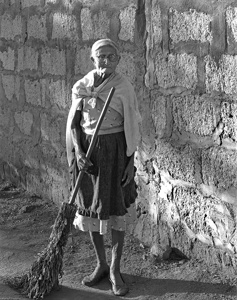 Emma, 86. I was being escorted around town by one of the villagers when we came upon Emma, who was furiously sweeping the dirt in the early morning light. "Emma," my companion shouted to her, "Emma, stand still!" She did but only for as long as I could set up the camera and make a single exposure. When Emma heard the shutter snap shut, she turned back to attacking the dirt in front of her house.