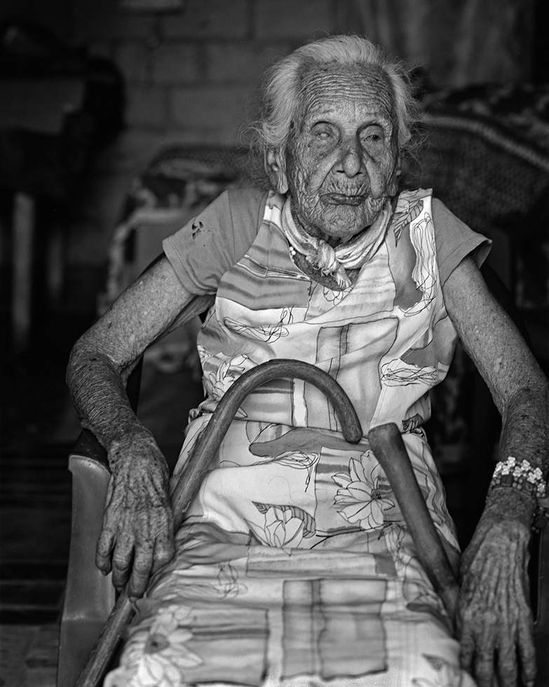 Rosa, 105, was the oldest resident of the village. One of her family members produced her birth certificate to verify it. Prior to my arrival her family had bathed Rosa and helped her into her nicest dress. All of the excitement and activity clearly had tired Rosa out, because as I began to make her photo she started leaning to the side, unable to keep herself upright. As she tottered, someone who I hadn’t noticed off to the side suddenly used a hand to gently push her back into position.
